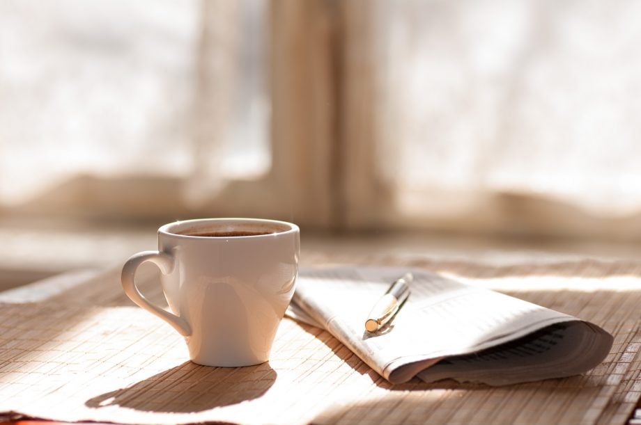 kaffeetasse-neben-einer-zeitung-auf-einem-holztisch
