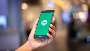 Eine Hand hält ein Smartphone, auf der die LINE App geöffnet ist.