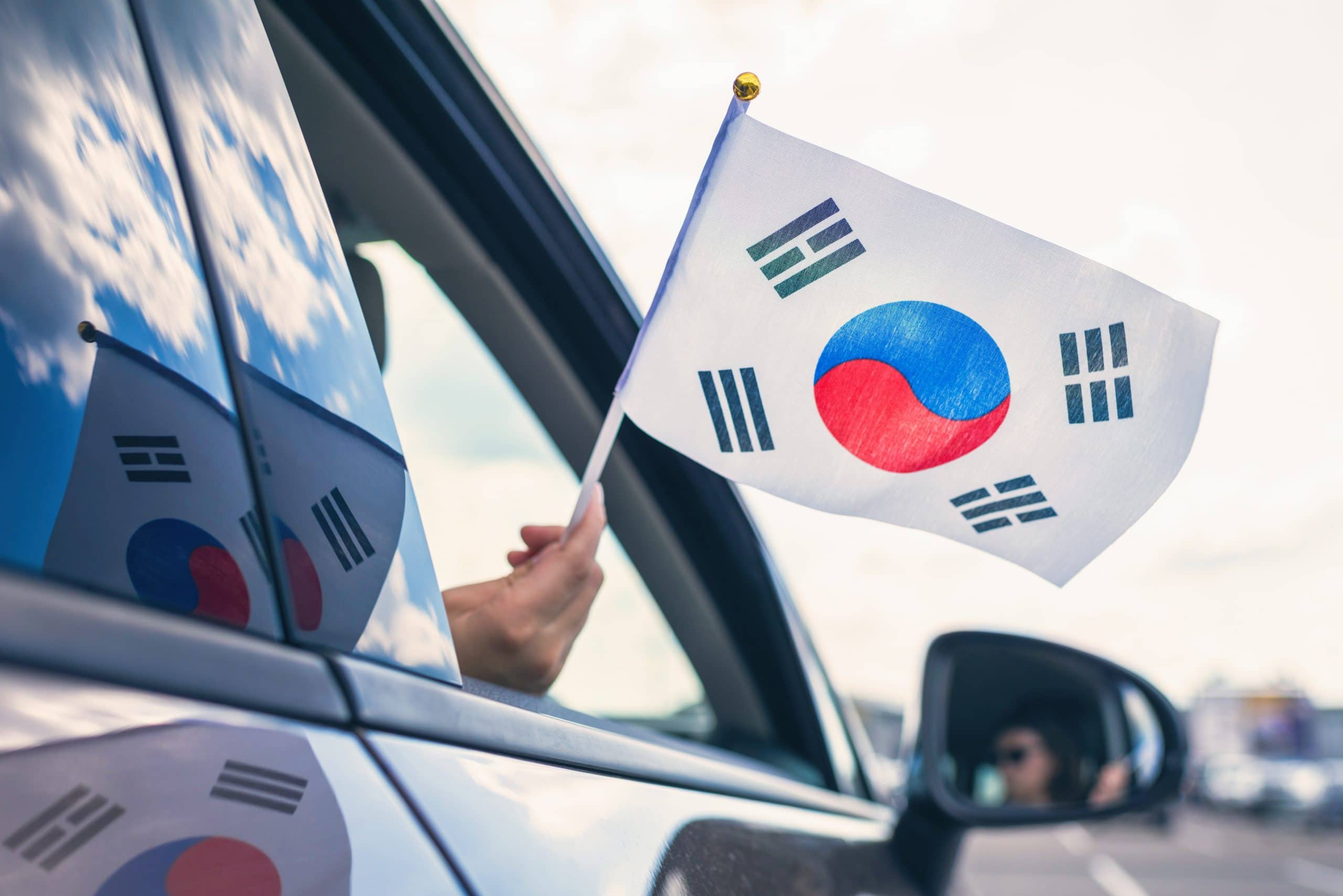 Südkorea-Flagge, die aus einem offenen Autofenster gehalten wird