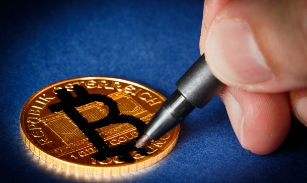 Goldunze wird mit Bitcoin-Zeichen übermalt