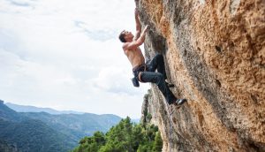 Mann klettert an Felswand hoch
