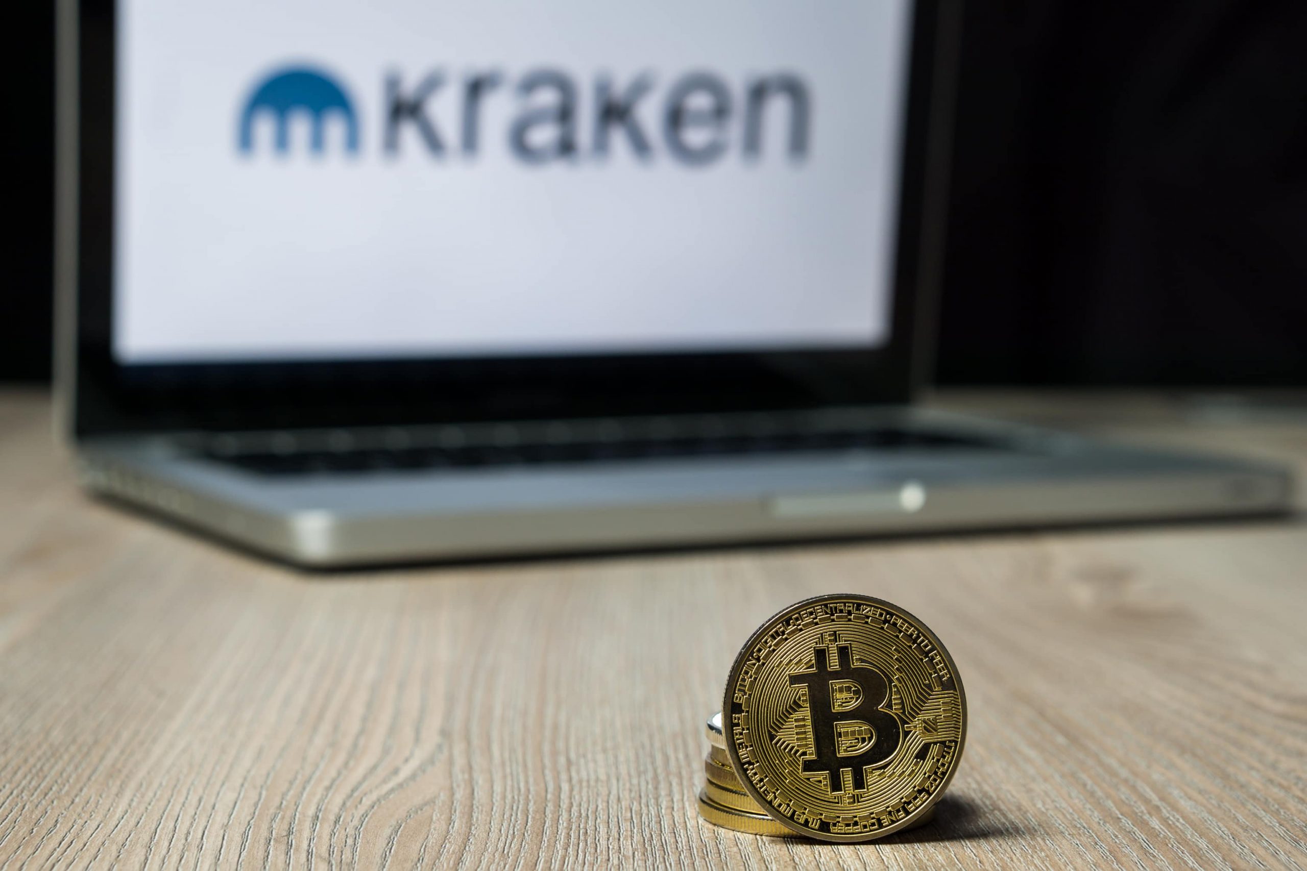 Bitcoin vor Laptop mit Kraken-Logo