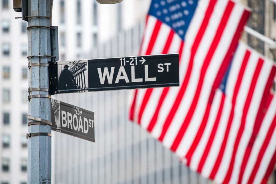 Finanzierung: Valentus baut Fonds mithilfe von Private-Equity-Token auf Wall-Street-Schild mit US-amerikanischer Flagge im Hintergrund