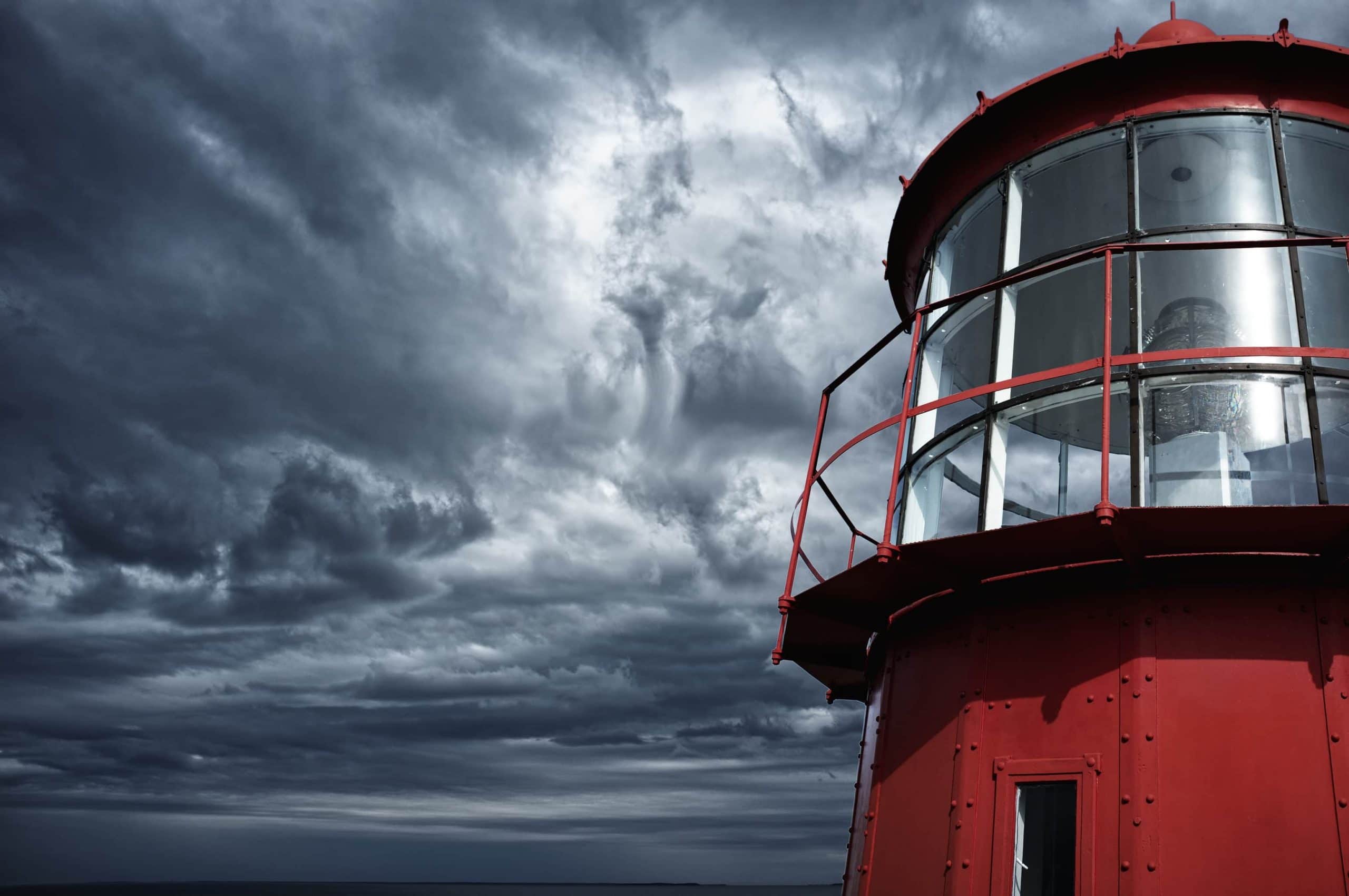 Ein roter Leuchtturm vor einem wolkenverhangenem Himmel