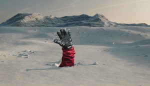 Der Arm eines Ski-Fahrers ragt aus einer Schneedecke