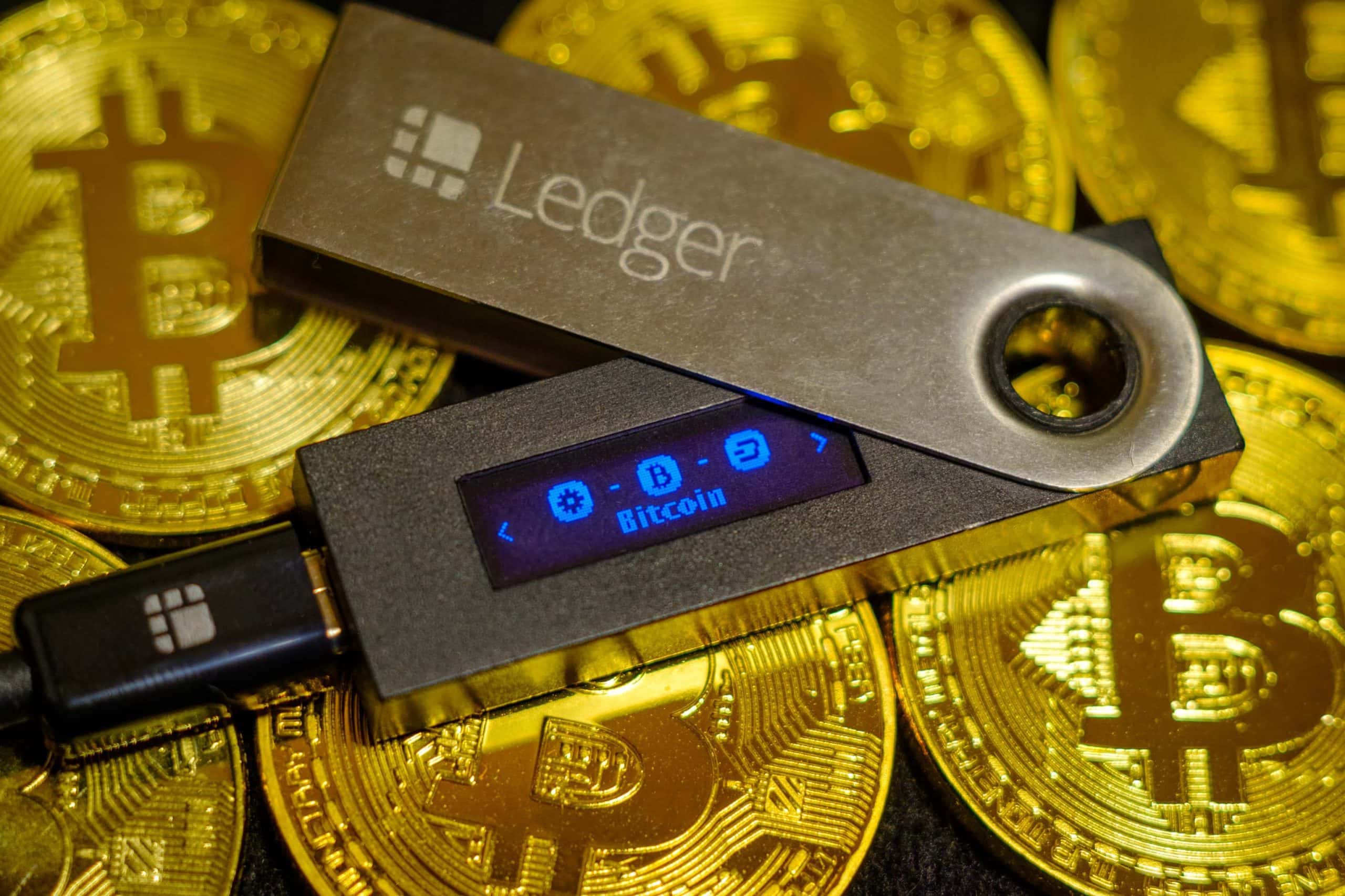 Eine Ledger-Hardware-Wallet liegt auf Bitcoin-Münzen