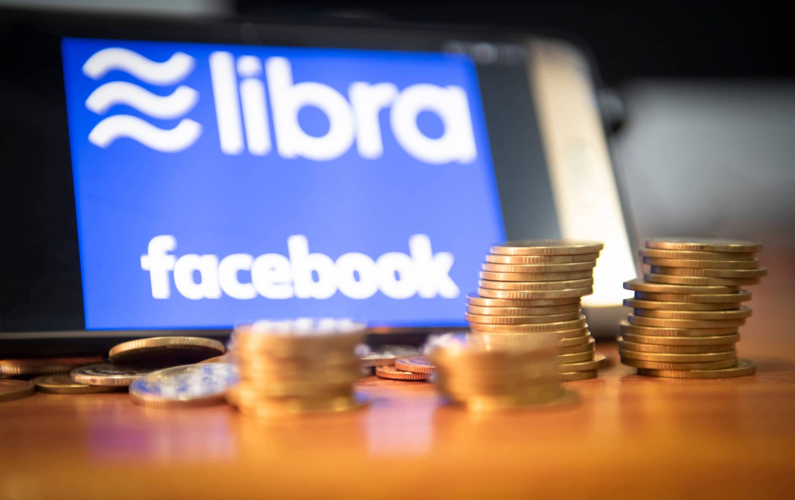 Mehrere Münzstapel, im Hintergrund ein Tablett mit den Logos von Libra und Facebook