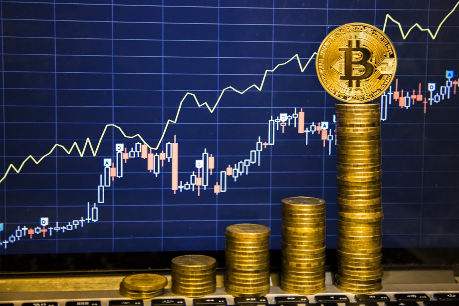 Bitcoin-Marktkapitalisierung erreicht Allzeithoch Bitcoin-Münzen vor einem Chart