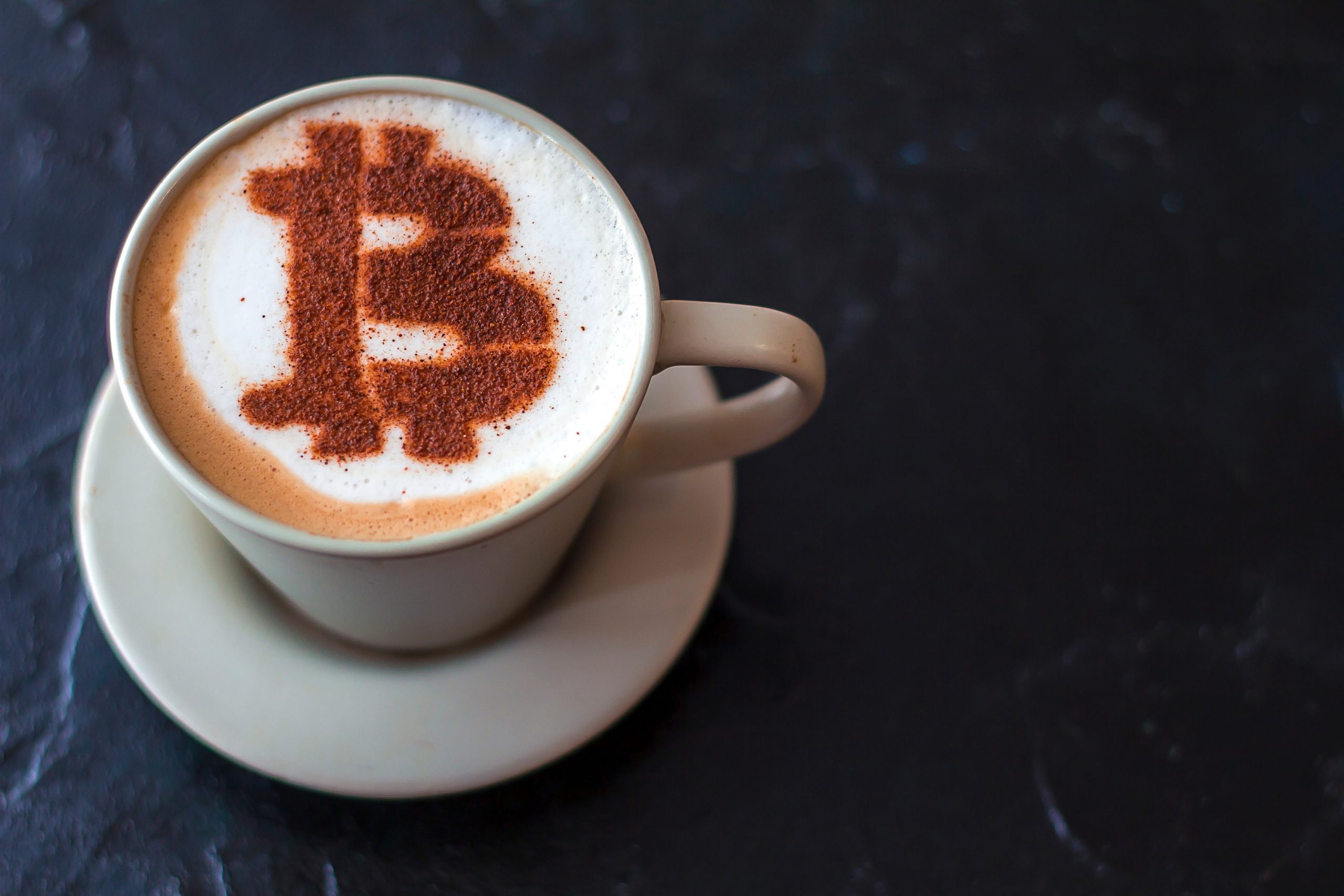 coffee cappuccino in a white cup with a symbol Bitcoin of cinnamon on milk foam