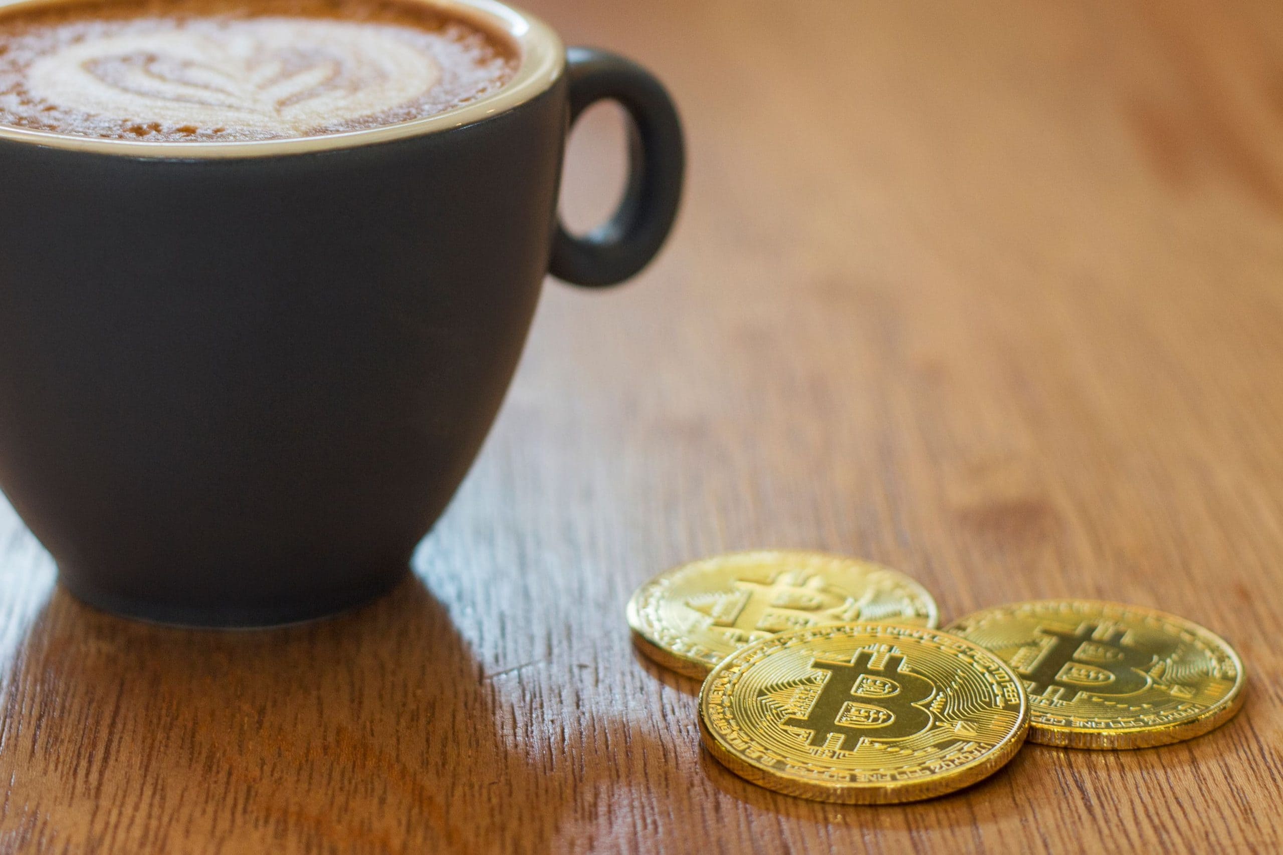 concept of business trading latte coffee with pieces of golden bitcoin Cryptocurrency in a cafe