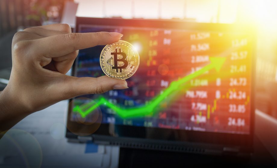 Passives Einkommen: Ein Weg den Wert deiner Bitcoin exponentiell zu steigern Bitcoin Münze wird vor Chart gehalten