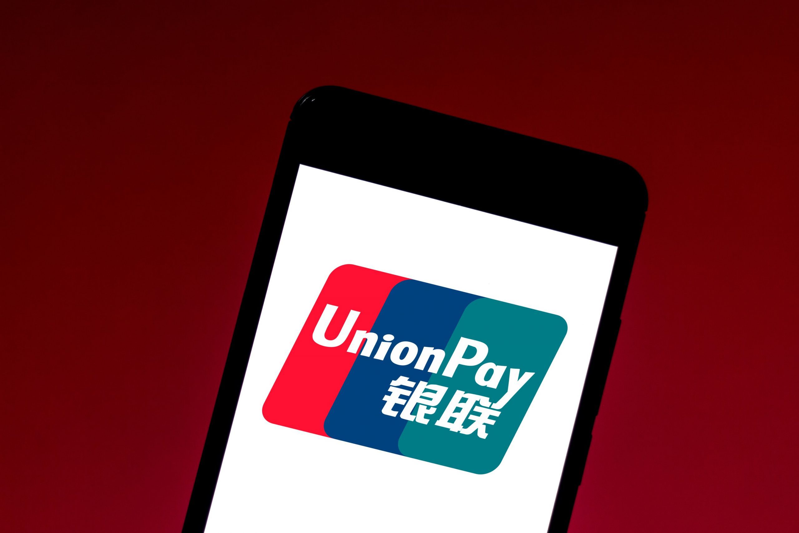 Smartphone mit UnionPay-Logo vor rotem Hintergrund