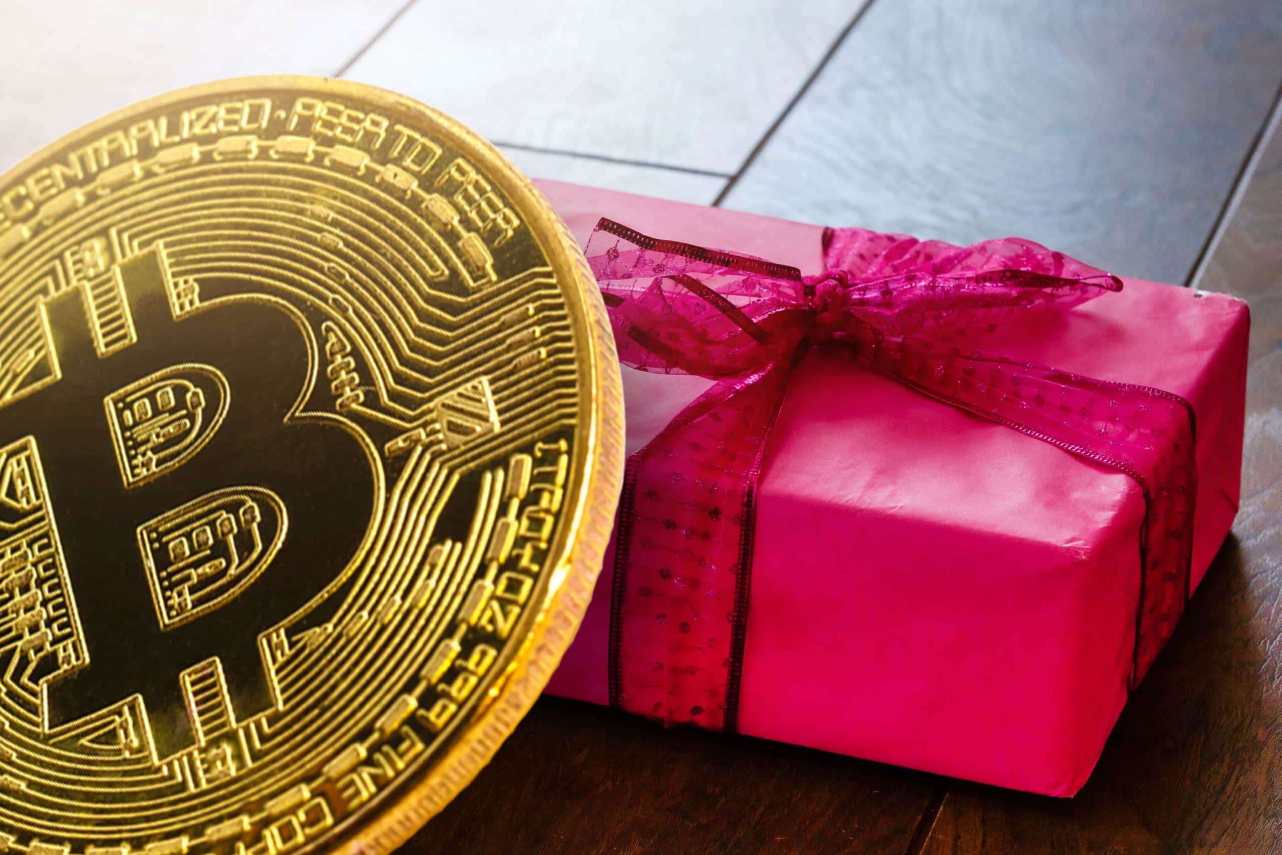 Bitcoin Münze vor einem roten Geschenk