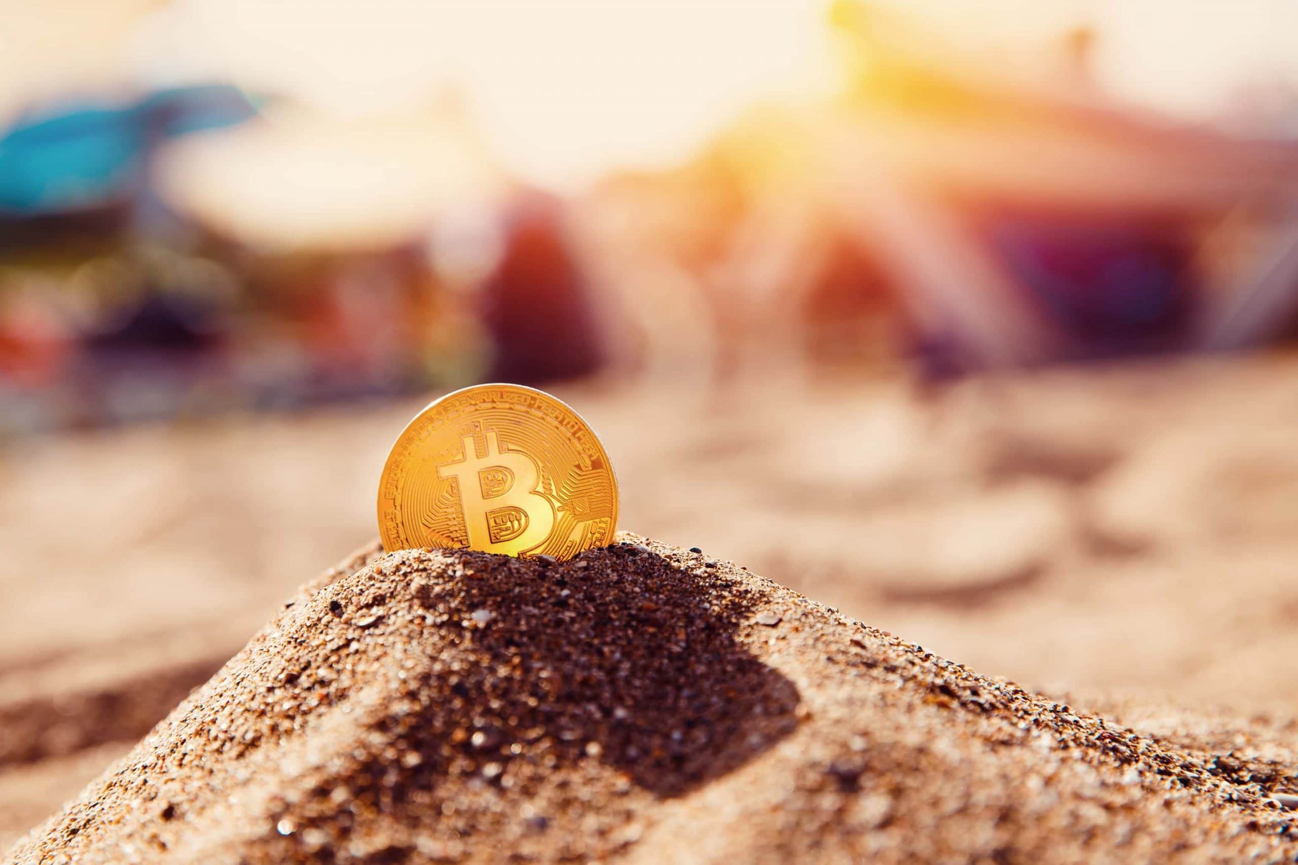 Bitcoin-Münze steckt im Sandhaufen