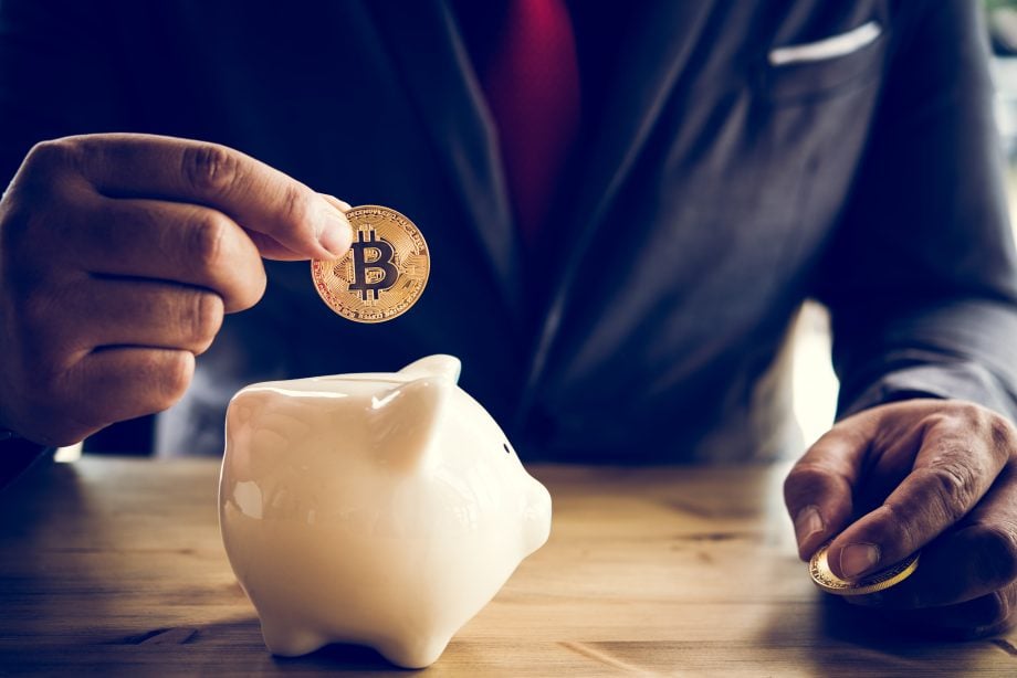 US-Versicherer MassMutual steigt gleich doppelt in Bitcoin (BTC) ein Ein Geschäftsmann steckt eine Bitcoin-Münze in ein Sparschwein