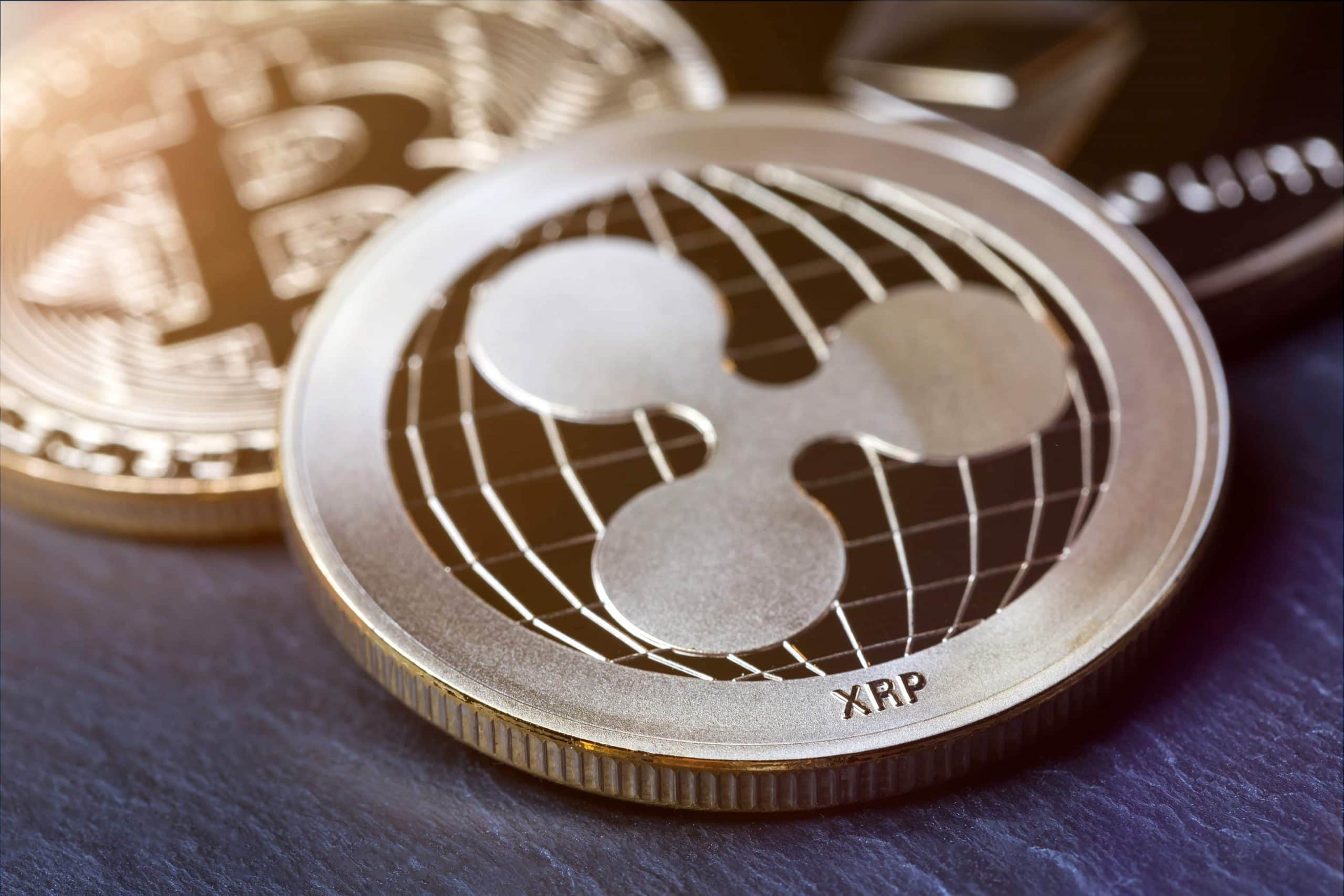 Ripple und Bitcoin auf einem dunkeln Holzuntergrund.