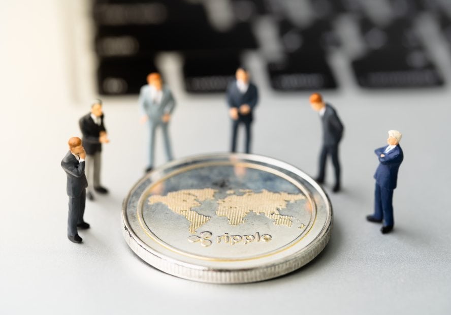 Forscher stellen Sicherheit des Ripple-Netzwerks in Frage Geschäftmänner stehen um Ripple Token herum