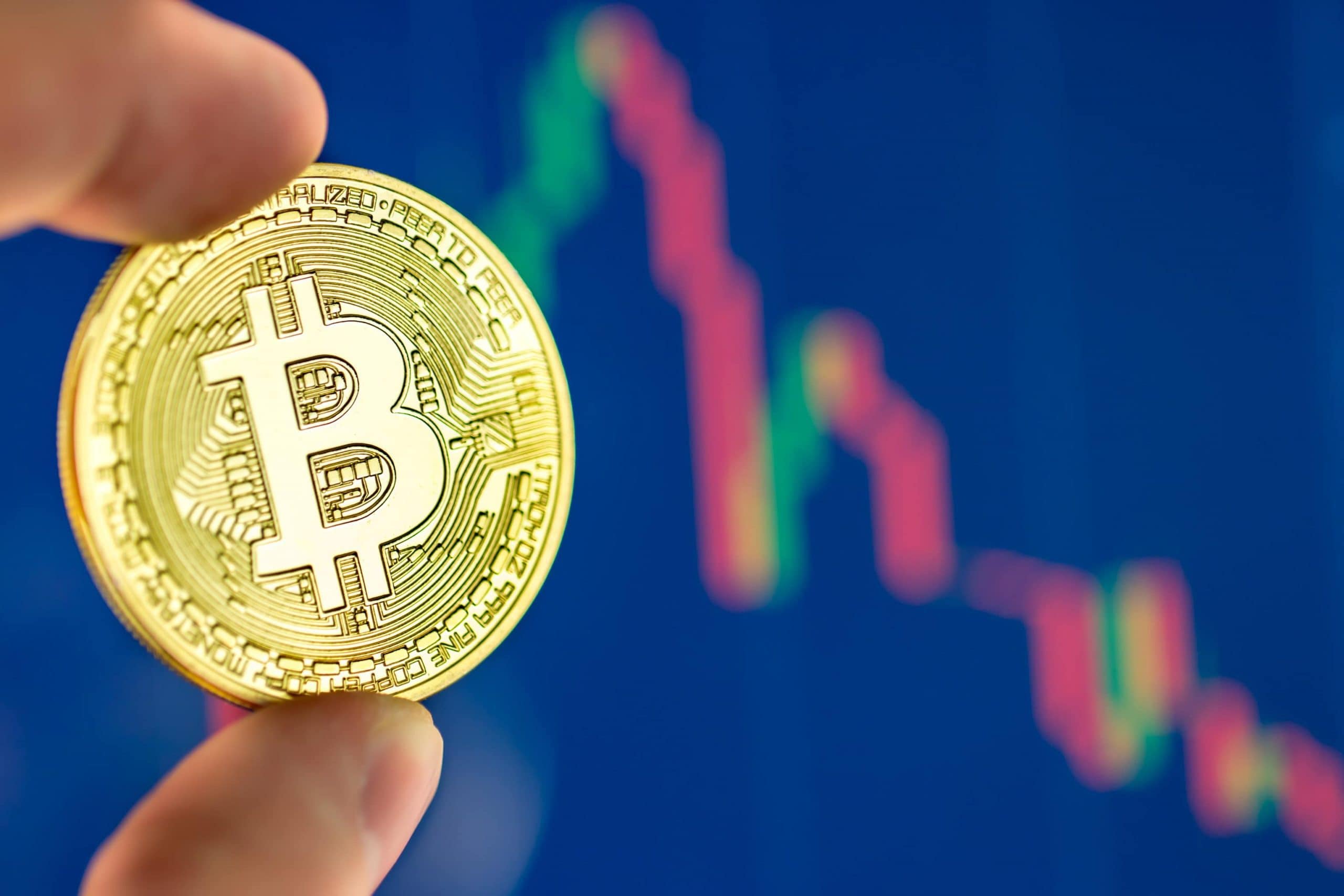 Bitcoin-Münze wird vor einem Chart gehalten