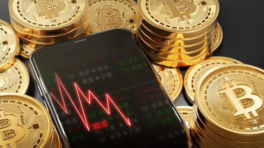 Abverkauf bei Bitcoin (BTC) und Altcoins – diese Szenarien sind möglich Ein roter fallender Chart auf einem Smartphone, das von Bticoin-Münzen umgeben ist