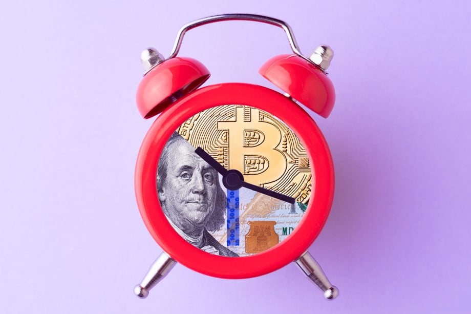 Bitcoin bei der Bank kaufen: In den USA bald Realität? Roter Wecke, das Ziffernblatt bildet eine Collage aus Bitcoin und US-Dollar Fotos