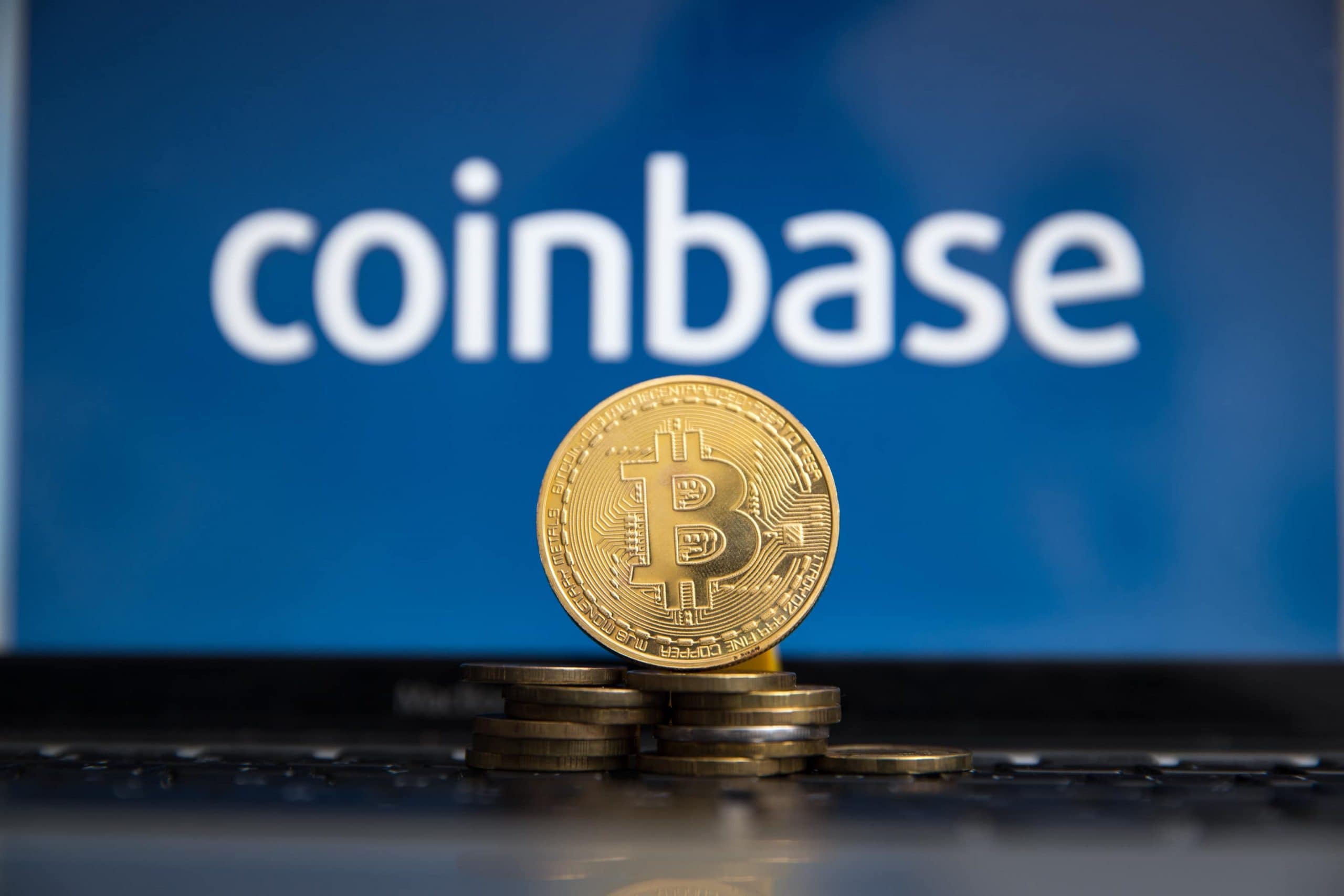 Bitcoin-Münze, im Hintergrund das Coinbase-Logo