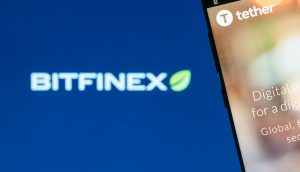 Tether-Logo auf einem Cmartphone vor Bitfinex-Logo