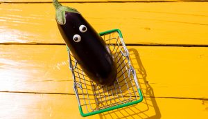 Eine Aubergine mit Augen in einem Einkaufskorb