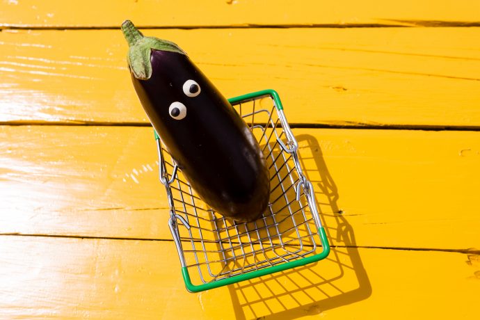 Eine Aubergine mit Augen in einem Einkaufskorb