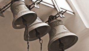 Drei Glocken hängen in einem Kirchenturm.