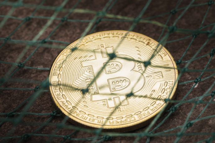 Bitcoin-Münze unter einem Netz