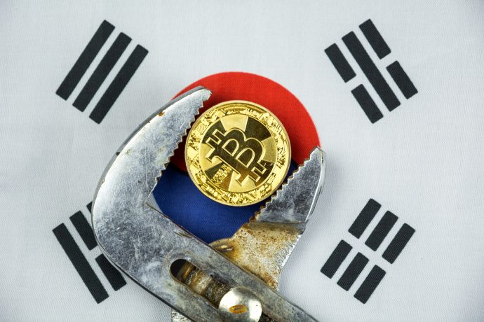 Bitcoin-Münze in Rohrzange vor südkoreanischer Flagge