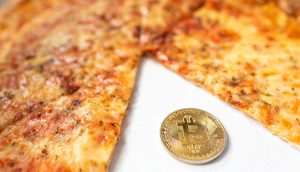 Bitcoin-Münze neben einer geschnittenen Pizza