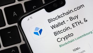 Auf einem Smartphone-Bildschirm ist die App von Blockchain.com geöffnet. Das Handy liegt auf einer Computertastatur.