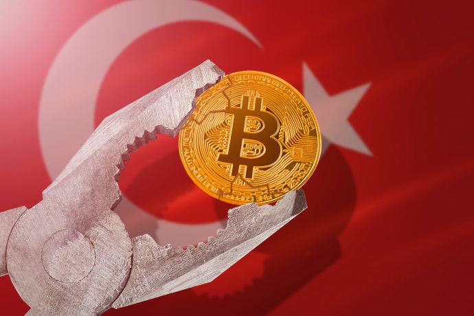 Bitcoin-Münze in Schraubzwinge vor türkischer Flagge