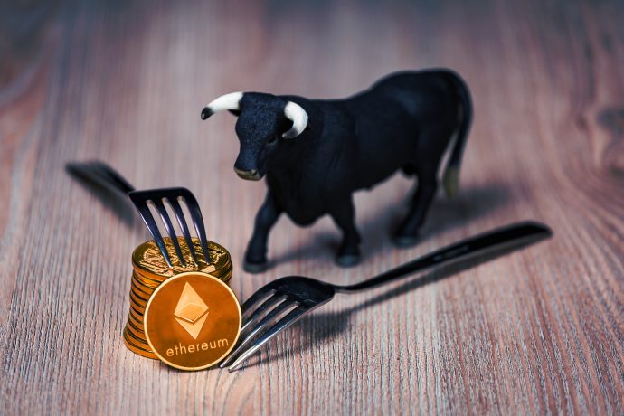 Stapel mit Ethereum-Münzen, daneben eine Bullenfigur und Gabeln (Symbolbild Berlin hard Fork)