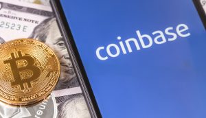 Ein Smartphone-Bildschirm zeigt das Coinbase-Logo. Daneben liegen US-Dollar-Noten und eine Bitcoin-Münze.