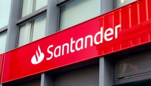 Das Logo der Santander Bank auf einer roten Tafel vor einer Gebäudefassade.