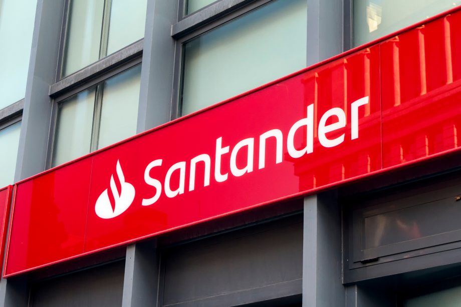 Das Logo der Santander Bank auf einer roten Tafel vor einer Gebäudefassade.