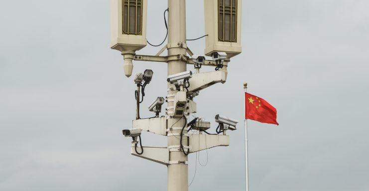 Ein Mast mit Überwachungskameras, daneben weht eine chinesische Flagge.