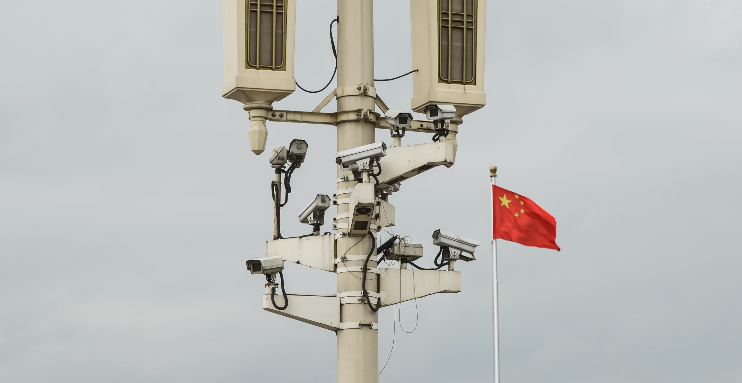 Ein Mast mit Überwachungskameras, daneben weht eine chinesische Flagge.