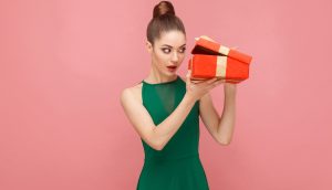 Frau schaut in eine Geschenkebox, was den Inhalt der Blockchain ETF symbolisieren soll.