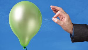 Hand hält Nadel an Luftballon