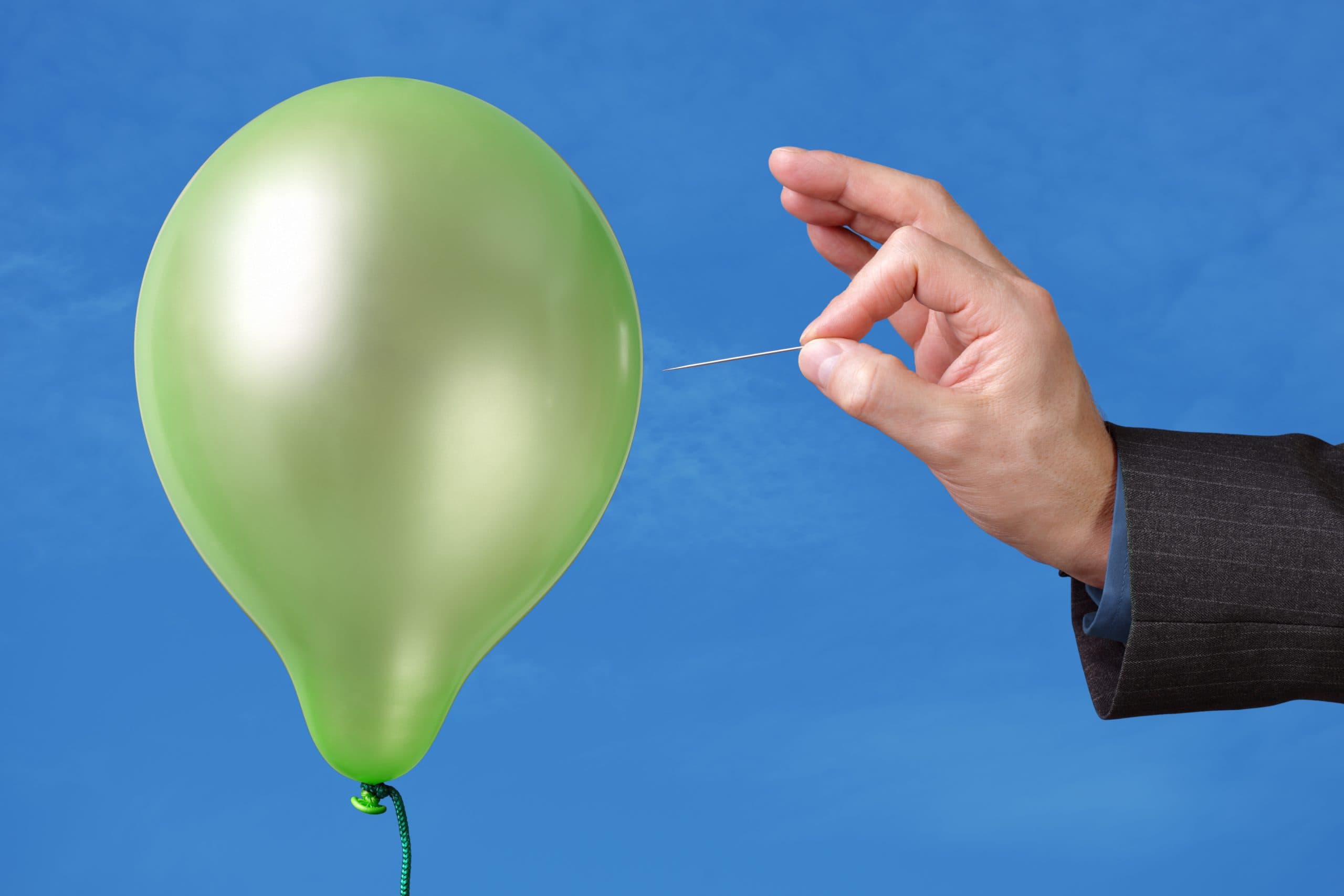 Hand hält Nadel an Luftballon