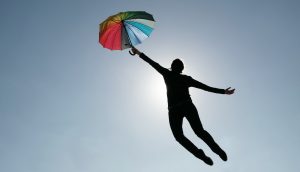 Mensch fliegt mit Regenschirm davon