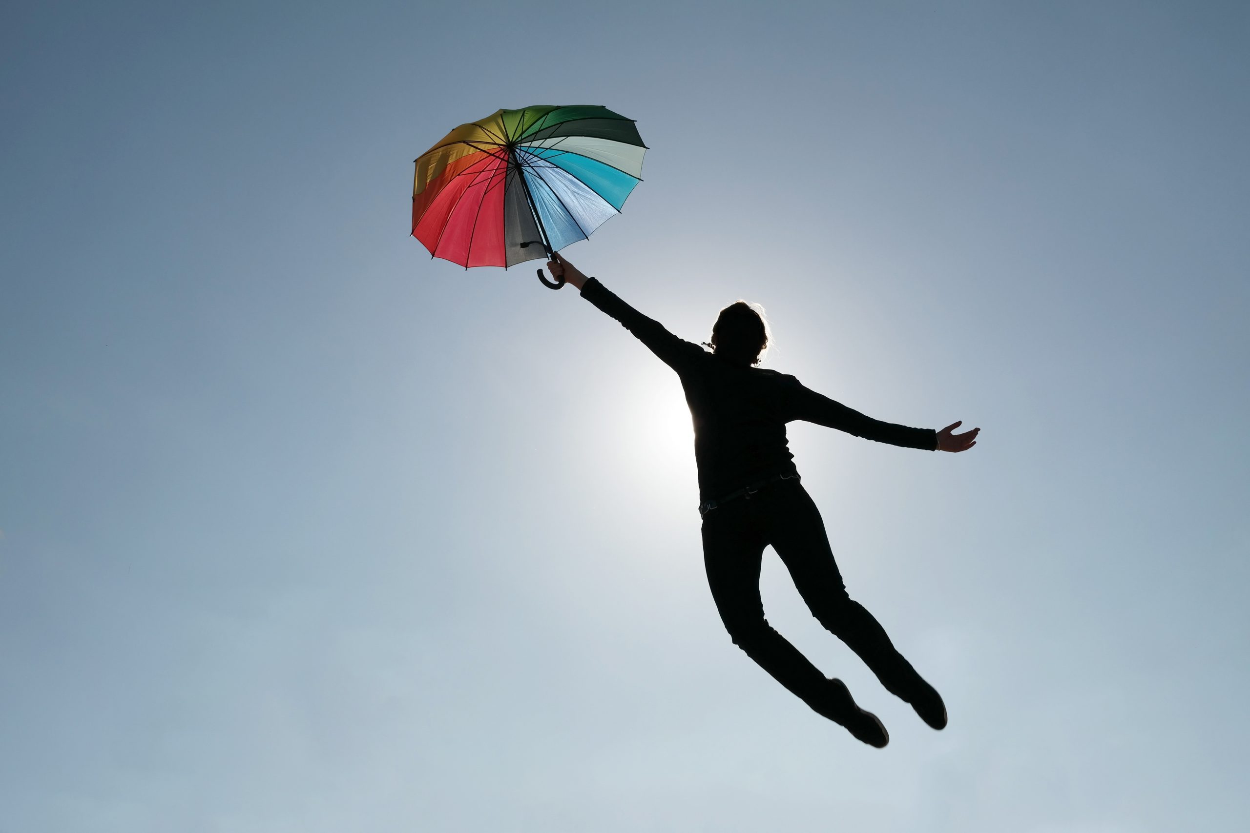 Mensch fliegt mit Regenschirm davon