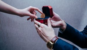 Ein Mann reicht einer Frau einen Bitcoin in einer Ringschachtel