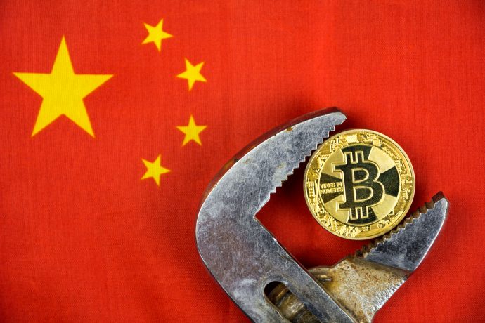 Bitcoin in Rohtzange, im Hitnergrund die chinesische Flagge