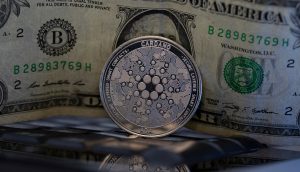 Eine Cardano-Münze steht vor einer US-Dollar-Note.