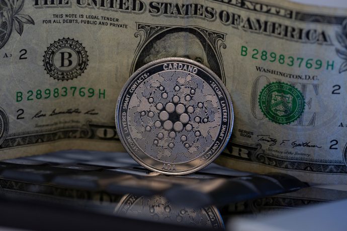 Eine Cardano-Münze steht vor einer US-Dollar-Note.