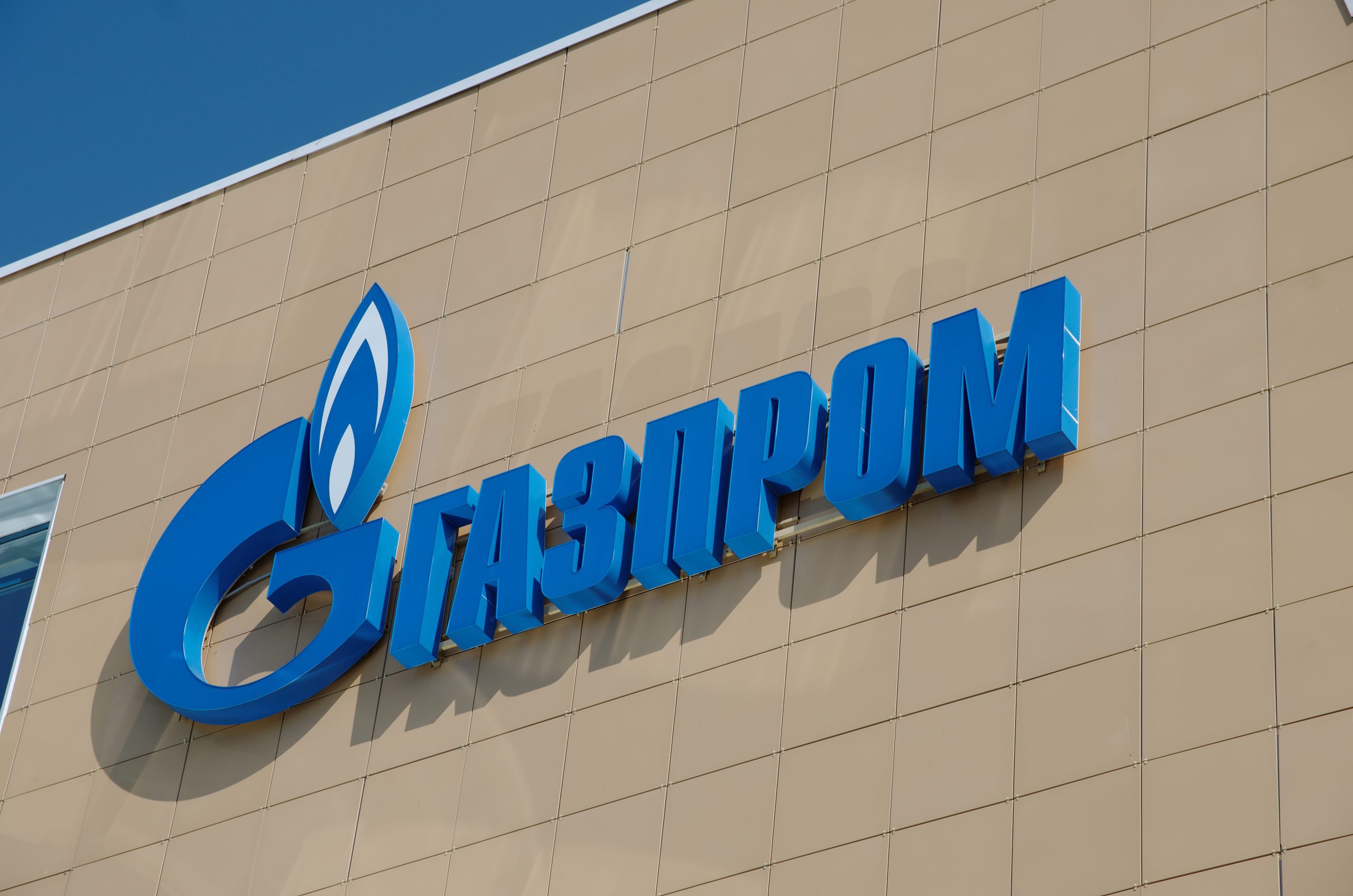 Das Logo von Gazprom in kyrillischer Schrift auf einem braunen Hintergrund.